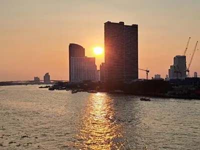 a city skyline with the sun setting behind tall buildings at BEAT Warii Hostel at Chaophraya River in Bangkok
