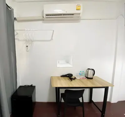 a table with two chairs and a heater on a wall at GO INN Siriraj Wang Lang - โก อินน์ ศิริราช ตลาดวังหลัง in Bangkok Noi