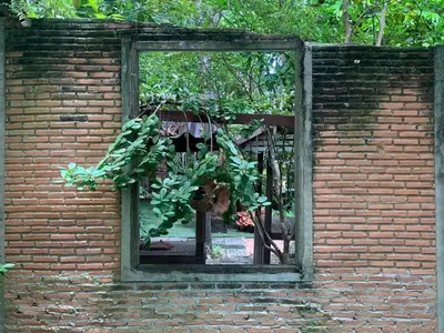 a brick wall with a window with a potted plant at Ruennakornin Homestay in Ban Bang Muang
