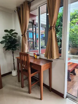 a wooden table and chair in front of a window at Sabai - Sabai in Bangkok