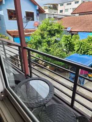a balcony with two chairs and a table and trees at Sabai - Sabai in Bangkok