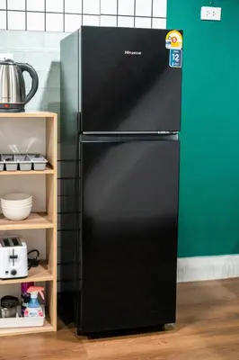 a black refrigerator in a kitchen next to a green wall at The Sleepyard Sathorn 11 in Bangkok
