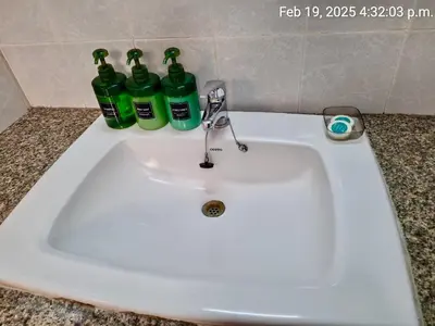 a white sink with three green bottles on a counter at Baan Arthit in Bangkok