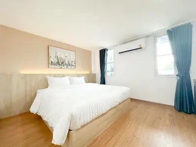 a bedroom with a large white bed with blue curtains at H-Banaat Hotel near Yanhee Hospital in Bangkok