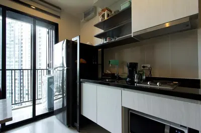 a kitchen with a refrigerator and a large window at BRAND New Sukhumvit Condo Cozy BTS in Bangkok