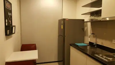 a kitchen with a black refrigerator and a red chair at BRAND New Sukhumvit Condo Cozy BTS in Bangkok