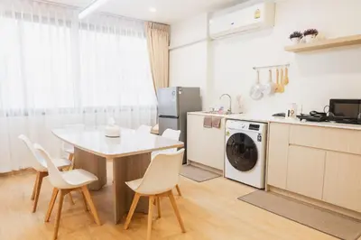 a kitchen with a table and a white table and chairs at Lotus Bear House - 1BR Loft in Bangkok