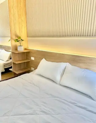 a bedroom with a white bed with a wooden headboard at KANYA Popular Condo in Ban Bang Phang