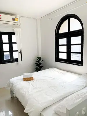 a white bed in a room with two windows at 1sabai in Bangkok