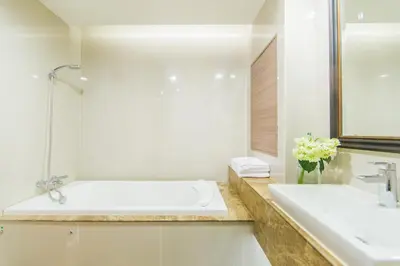 a white bathroom with a tub and a sink at Qiss Residence by Bliston in Bangkok