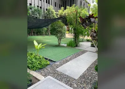 a garden with a green lawn in front of a building at Beautiful condo, BTS Thonglor, 5mins by walking in Bangkok