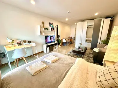 a bedroom with a bed and a desk and a living room at Cosy Studio near BTS in Bangkok