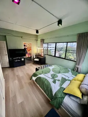 a bedroom with a large bed and a flat screen tv at Fab Rainbow Studio in Bangkok