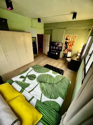 a bedroom with a bed with green and white sheets at Fab Rainbow Studio in Bangkok