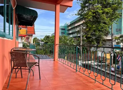 a balcony with chairs and a table and a fence at Papaya House Bangkok - Wat Arun in Bangkok Noi