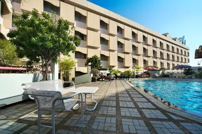 a hotel with a table and chairs next to a swimming pool at Royal Rattanakosin Hotel - Near Grand Palace & Khaosan Road in Bangkok