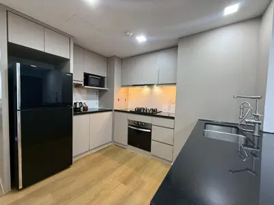 a kitchen with white cabinets and a black refrigerator at Civic Park in Bangkok