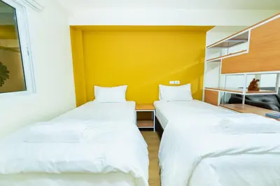 two beds in a room with a yellow wall at GL Sport Club Serviced Residence in Bangkok
