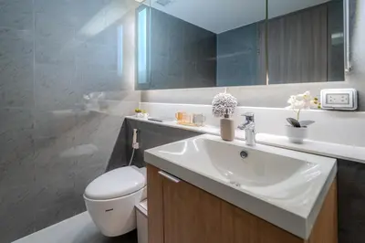 a bathroom with a sink and a toilet and a mirror at Luxury 2BR with Sky Pool & Gym Near BTS Thong lo in Bangkok