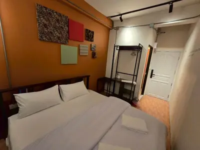 a bedroom with a large white bed and a mirror at Lhong Krung Hostel in Bangkok