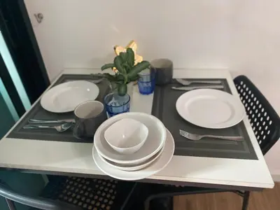 a table with white plates and utensils on it at Cozy Entire Apartment place in Ban Khlong Samrong