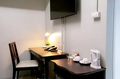 a small room with a desk with a phone on it at Annex Lumpini Bangkok in Bangkok