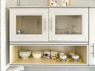 a white cabinet filled with dishes and cups on a shelf at 2 mins to SRT I Urban Hideaway near Park in Bangkok