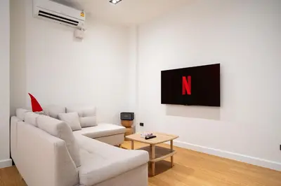 a living room with a couch and a tv on a wall at Townhouse in Khet Phayathai - Ari in Bangkok