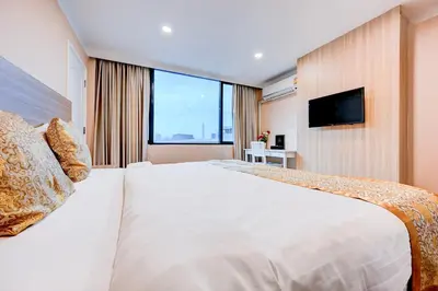 a hotel room with a large bed with a television at Dancenter Bangkok Travellers Hotel in Bangkok