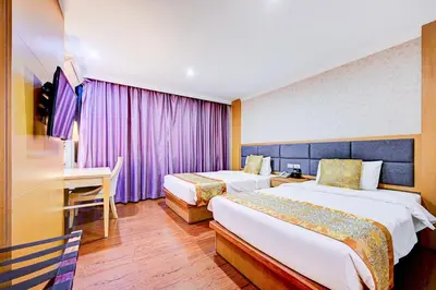 a hotel room with two beds and a desk at Dancenter Bangkok Travellers Hotel in Bangkok