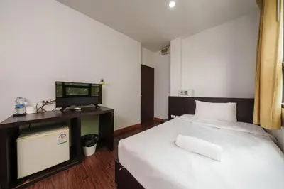 a bedroom with a bed with a desk and a television at Dancenter Khaosan Park Hotel in Bangkok