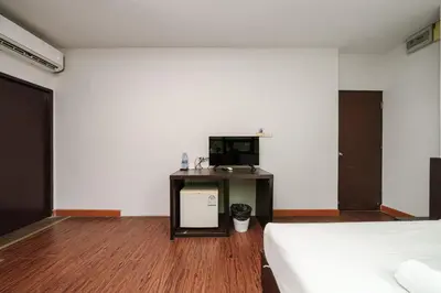 a room with a bed and a desk with a tv at Dancenter Khaosan Park Hotel in Bangkok