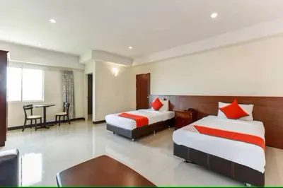 a hotel room with two beds and a table at Dancenter VResotel in Bangkok