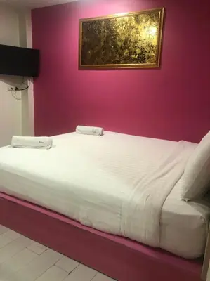 a large white bed in a room with a purple wall at The Seven Luck in Bangkok