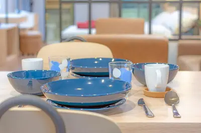 a table with blue bowls and cups and spoons at Private apartment in Huaikwang in Bangkok