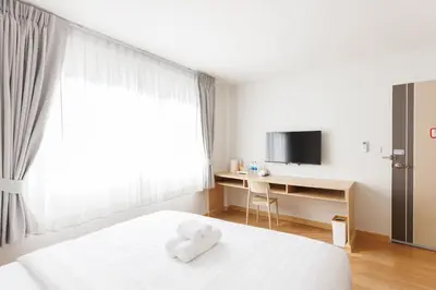 a bedroom with a bed with a teddy bear on it at Takka Hotel - Bearing in Bangna