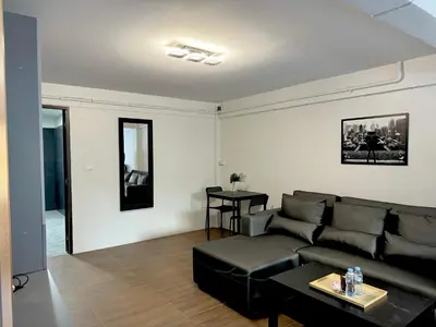 a living room with a black couch and a table at Berlin Haus in Nonthaburi