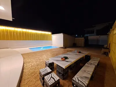 a patio with a table and chairs and a swimming pool at The Yellow House Poolvilla in Sathani Ban Hua Mak
