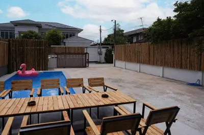 a backyard with a pool and wooden tables and chairs at Number 8 Poolvilla Bangkok in Sathani Ban Hua Mak