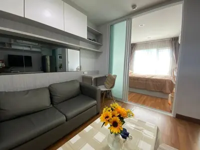 a living room with a couch and a table with flowers at Stunning Condo - BTS On Nut - Pool, Gym, Wi-Fi in Bangkok