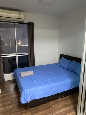 a bedroom with a bed with blue sheets and a window at Mari's space city view in Nonthaburi
