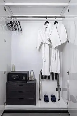a wardrobe with white robes and a television and shoes at Galleria 12 Sukhumvit Bangkok by Compass Hospitality in Bangkok