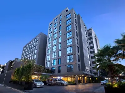 a tall building with cars parked in a parking lot at Galleria 12 Sukhumvit Bangkok by Compass Hospitality in Bangkok