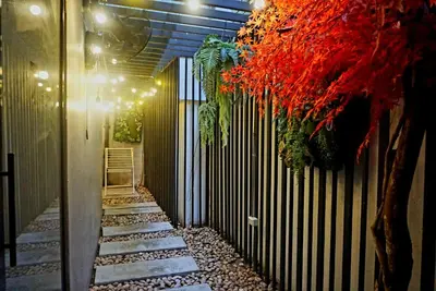 a walkway with a fence and a red tree at Hash Capsule Hostel Silom Soi 3 in Bangkok
