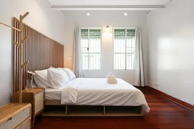 a bedroom with a large bed and two windows at Moondance House Chinatown in Bangkok
