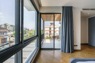 a living room with large windows and a view of a city at Designer 49 Pool Villa in Bangkok