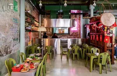 a restaurant with green chairs and tables and a bar at Best River view, Retro vibe studio apartment - Bangkok Old Town in Bangkok