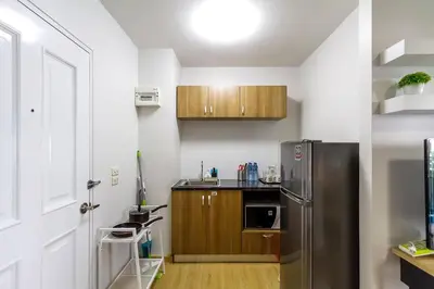 a kitchen with a stainless steel refrigerator and wooden cabinets at TC Contel At BTS Onnut Century in Amphoe Phra Khanong