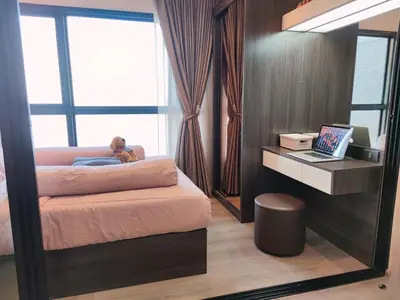 a man laying on a bed in a bedroom with a laptop at Luxury Riverside Condo, 3 SKY Pools , Close to MRT Train Station in Ban Sai Ma