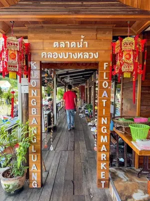 a man walking down a wooden walkway into a store at Apartment Near Big Buddha in Bangkok Yai